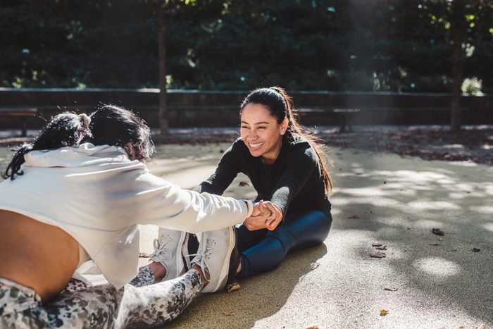 Female friends doing stretching together outdoor having fun.