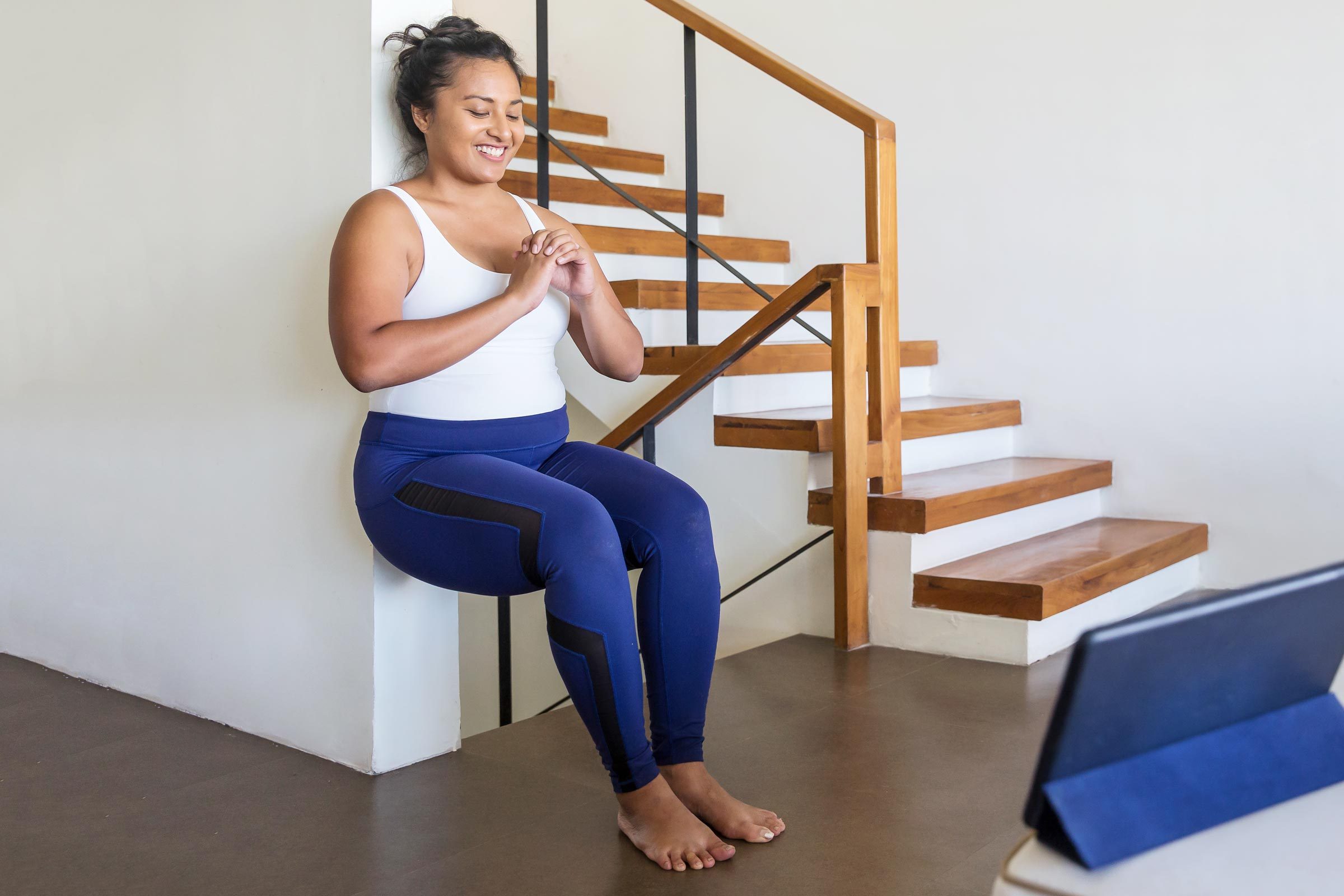 woman squatting against a wall doing exercises