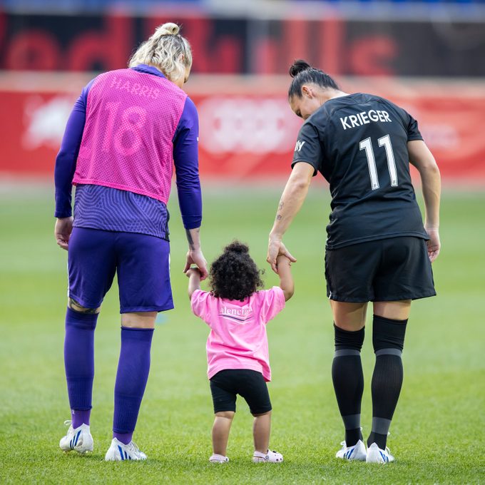 Ashlyn Harris And Ali Krieger hold the hands of their daughter Sloane after the NWSL Home Opener match against Racing Louisville FC at Red Bull Arena on May 22, 2022 in Harrison, New Jersey