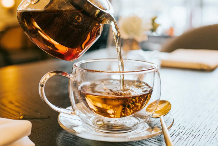 pouring tea into a clear cup from a clear tea pot