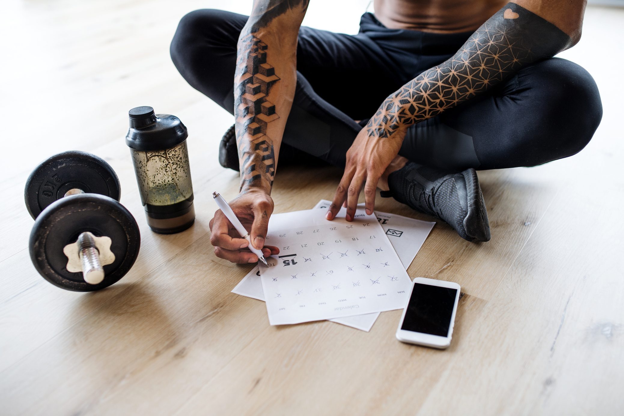 A midsection of fit mixed race man with smartphone doing exercise at home, checking progress.