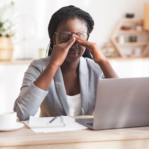 Overworked Black Businesswoman Massaging Nosebridge At Workplace Having Eyesight Problem