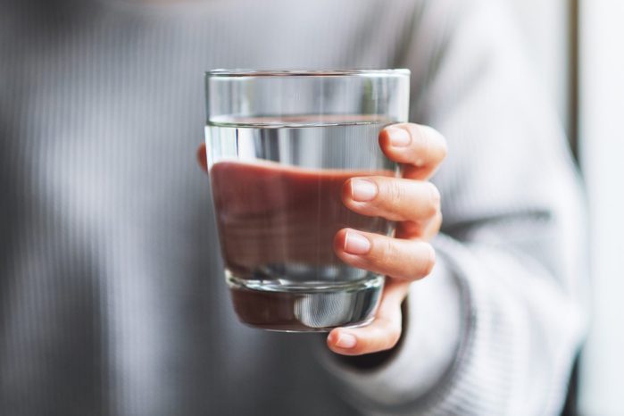 a woman holding a glass of pure water