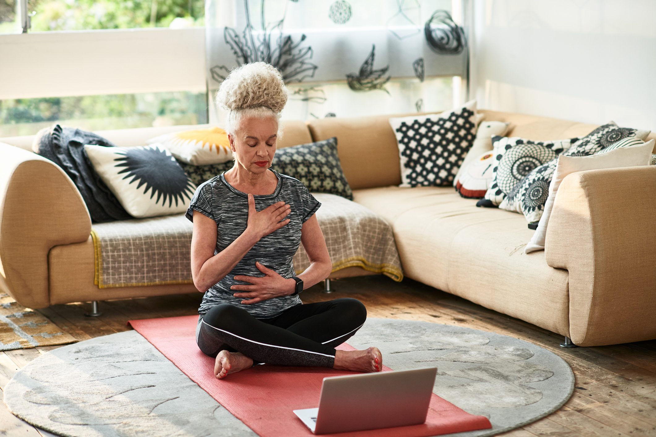 Grey haired woman concentrating on breathing exercises at home