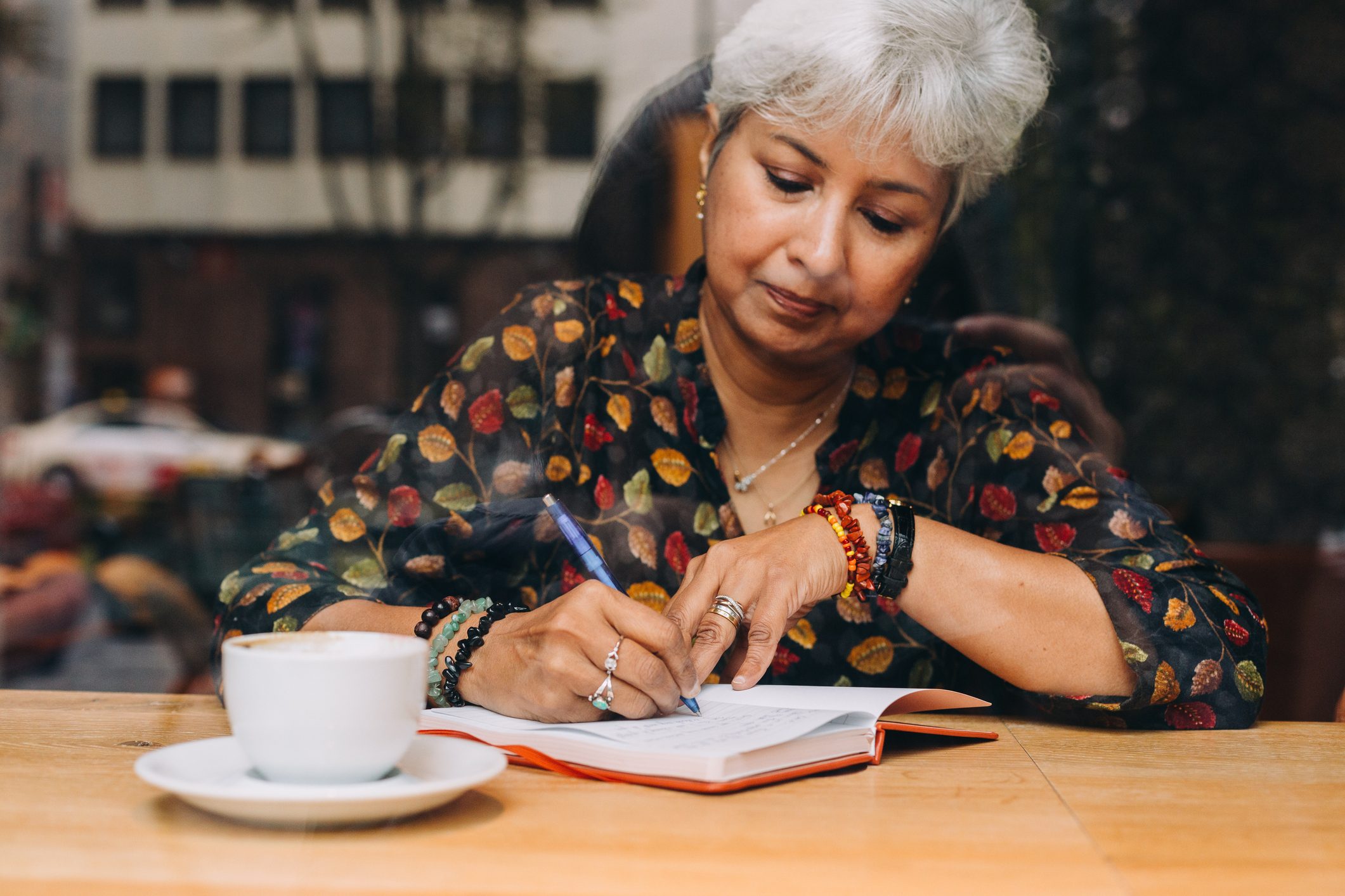 Middle Aged Woman Journaling In A Coffee Shop journaling