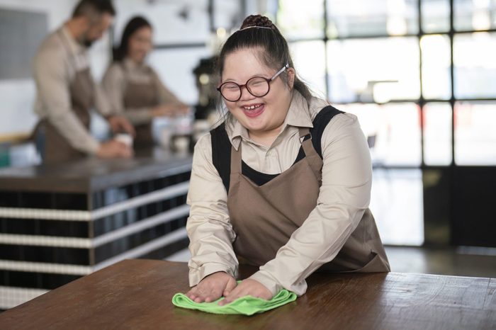 girl doing table slides with a green towel at a cafe