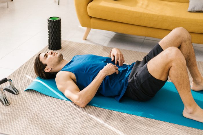 Young man lying on a mat doing pelvic tilts