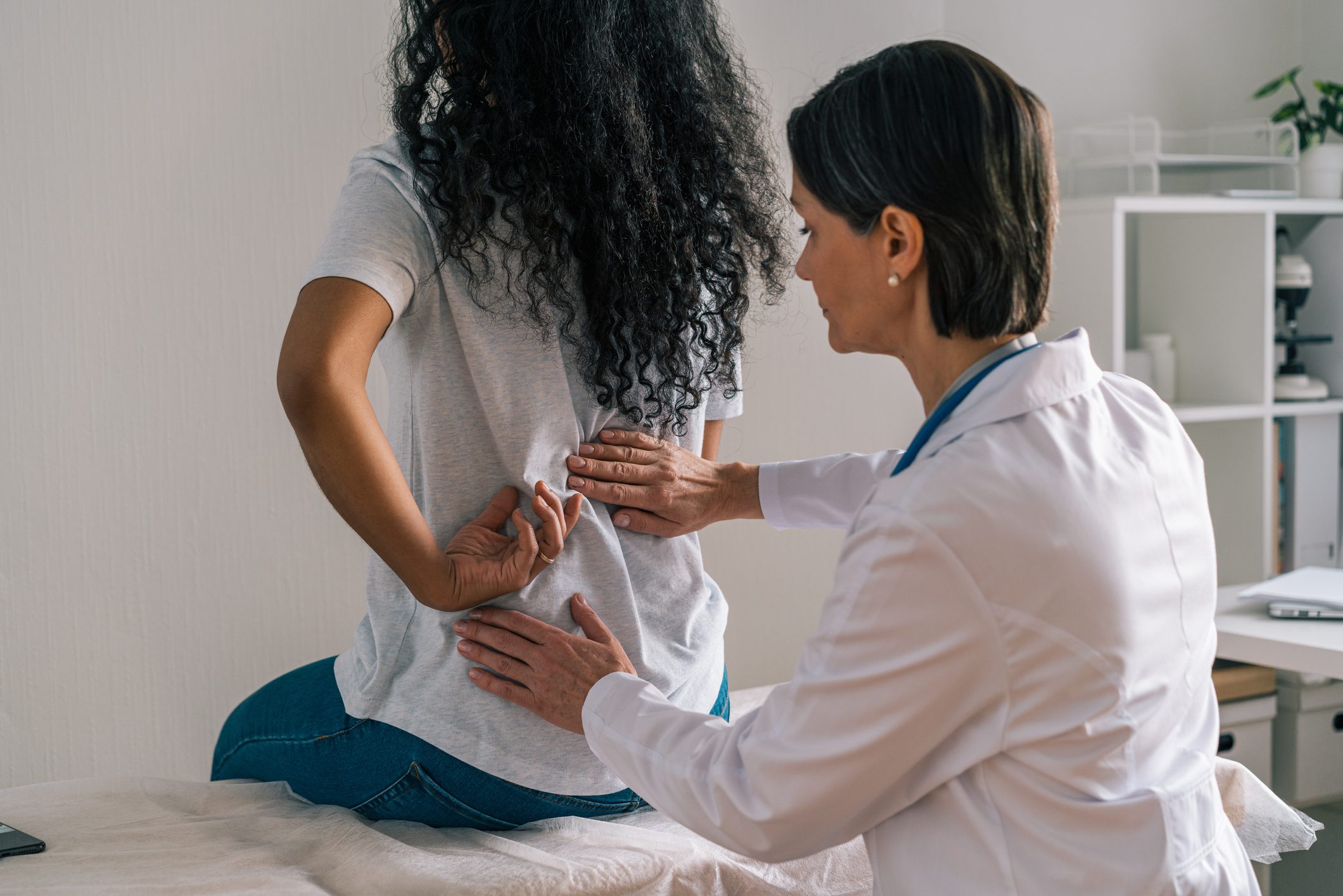 Faceless african-american patient complaining about back ache and rheumatism to orthopedist