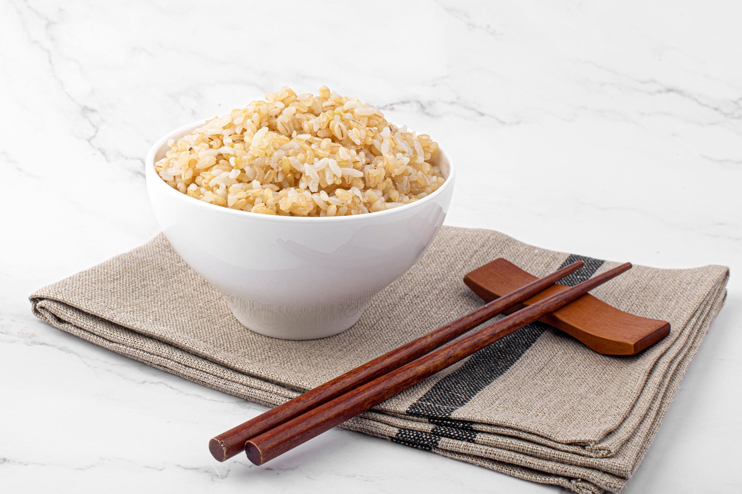 Brown rice in white rice bowl isolated on white background.