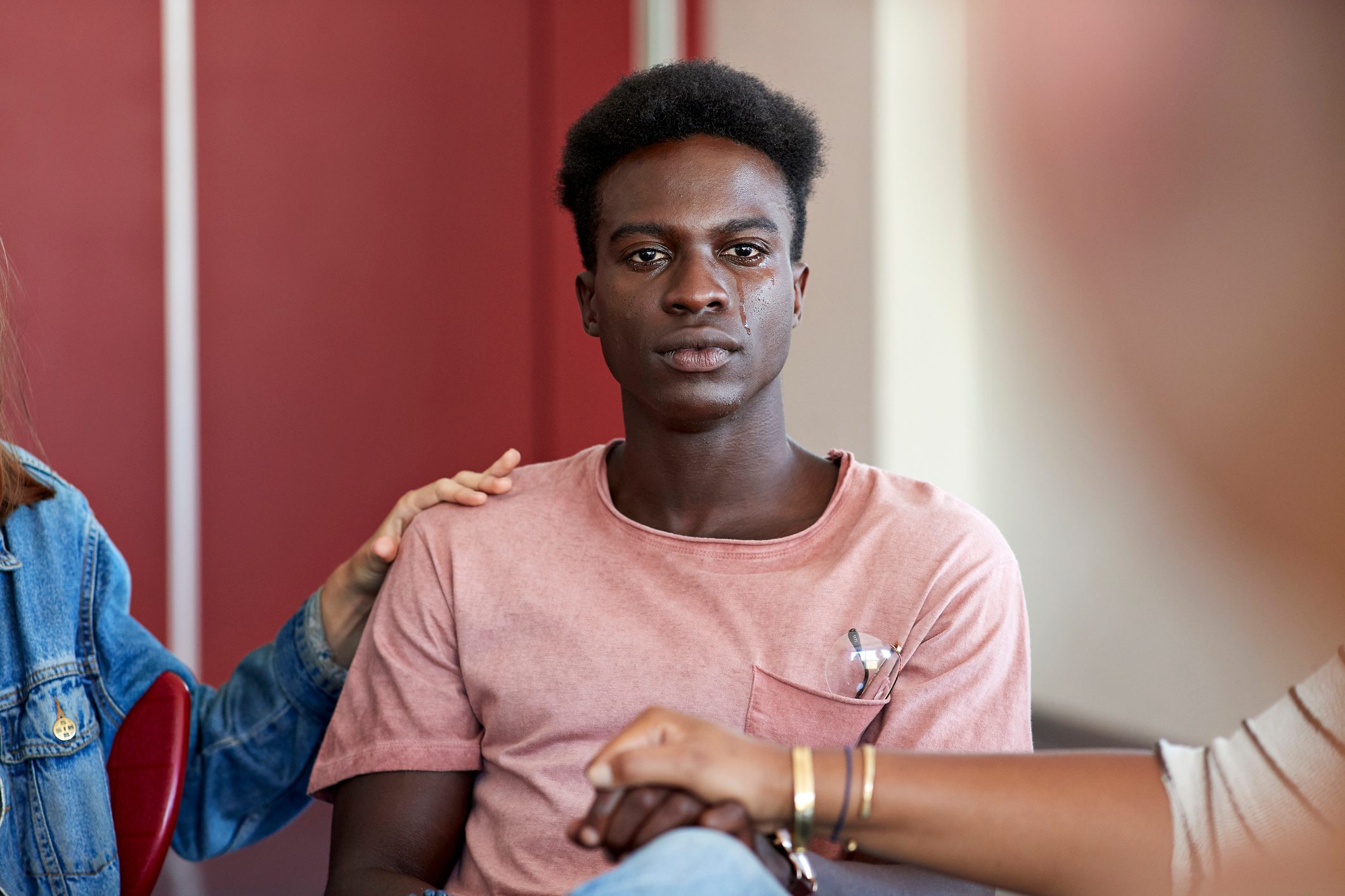 Sad man being consoled by friends in group therapy