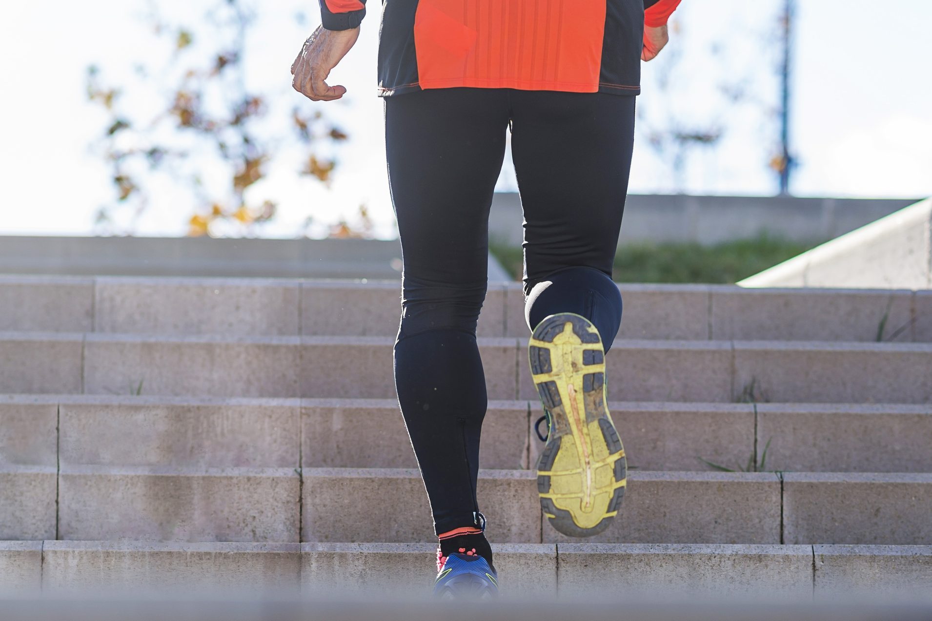 Rear view of a mature athlete training running up and down the stairs outdoors in a park in a sunny day