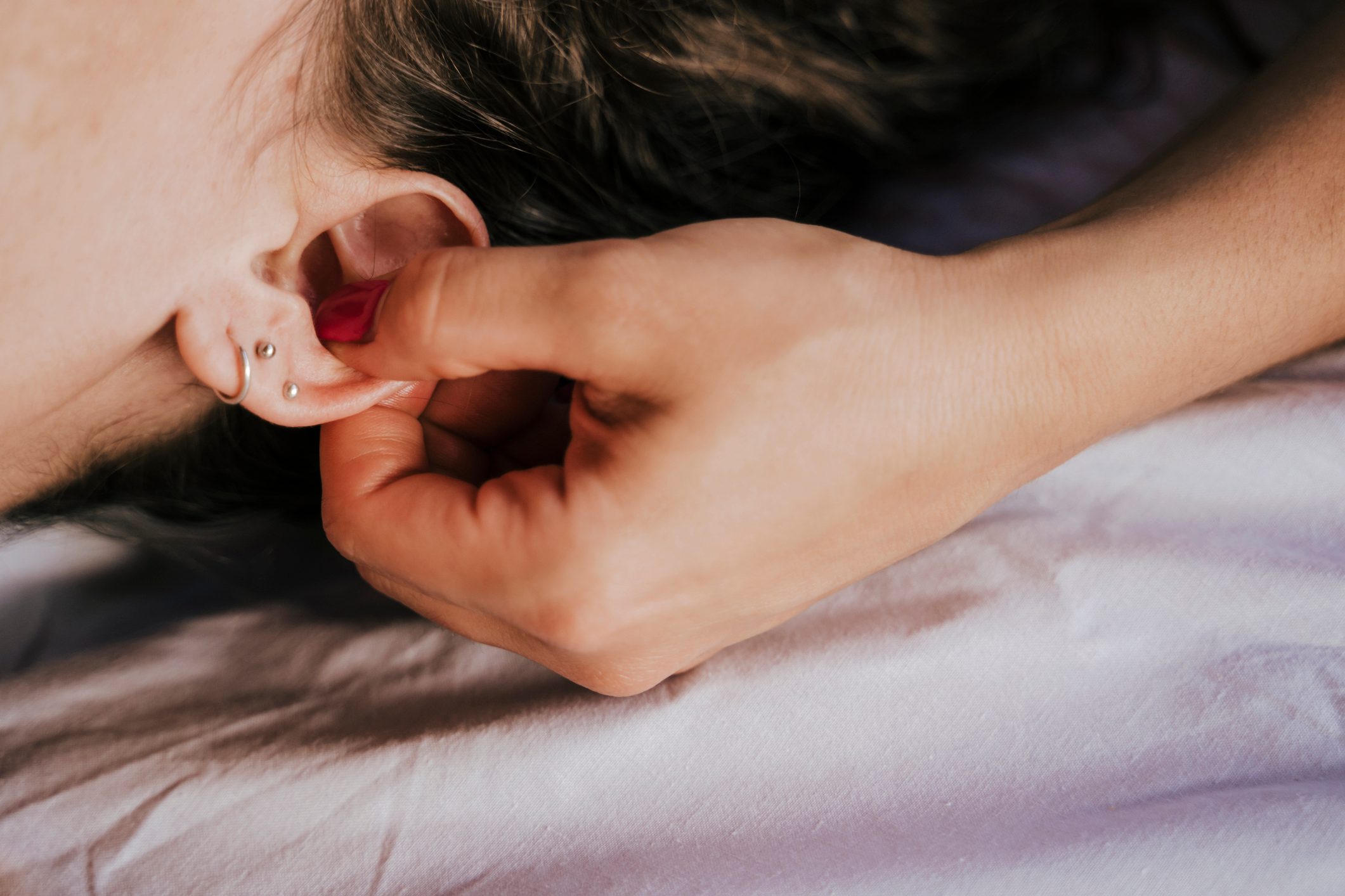 Close-up of female therapist giving ear massage to woman in health spa