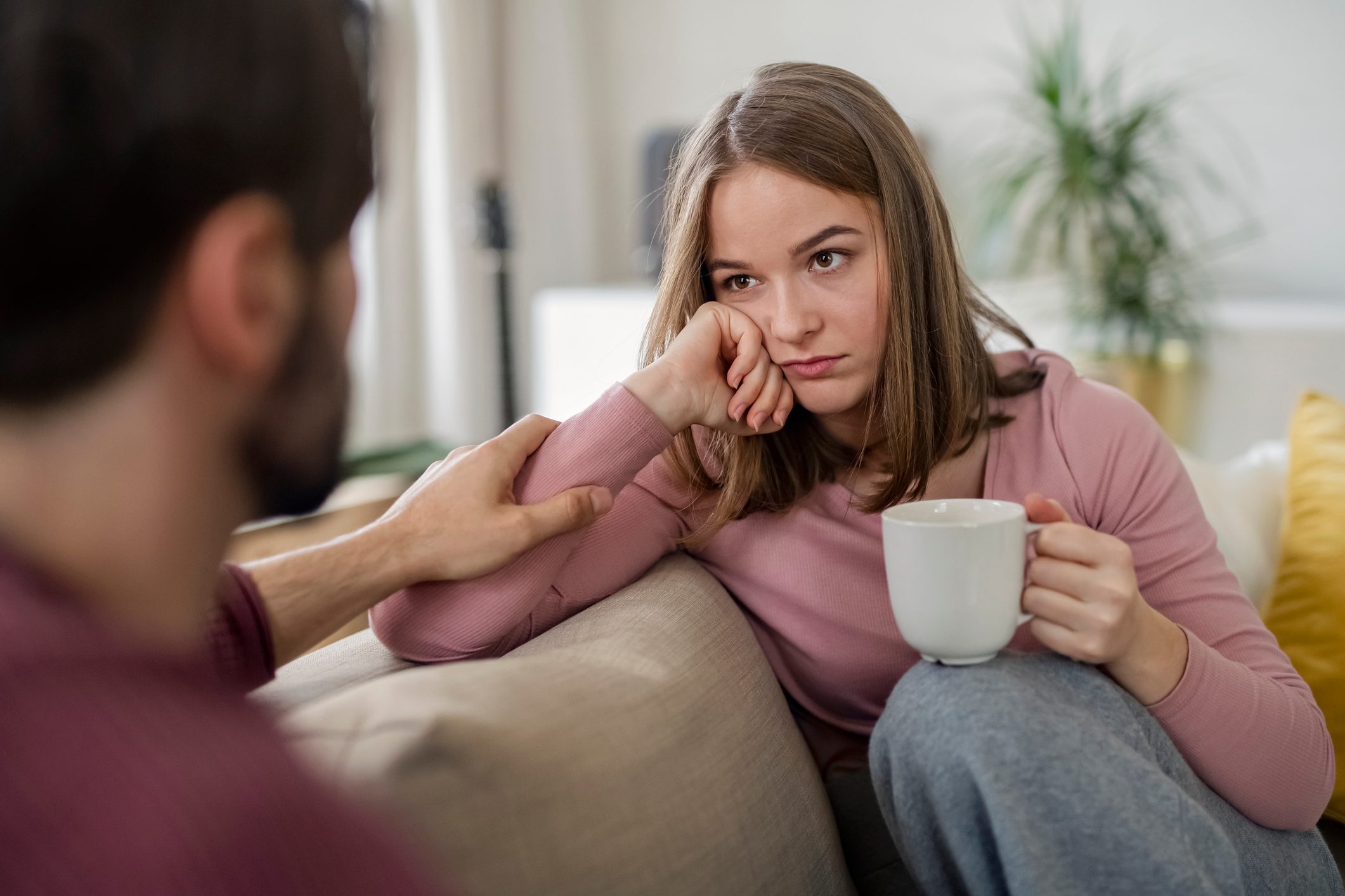 Upset young adults flatmates sitting indoors and talking.