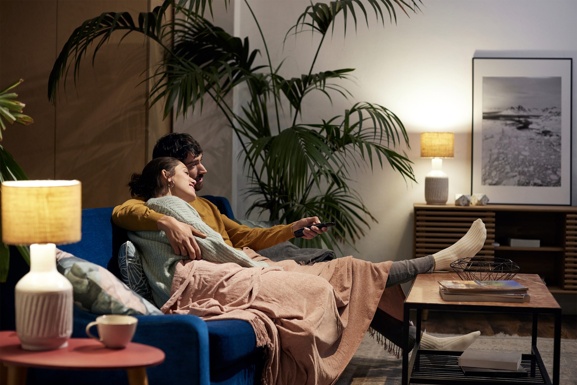 Relaxed couple sitting on sofa in living room watching TV