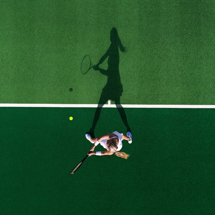 Drone shot above a female tennis player and her shadow, England, United Kingdom