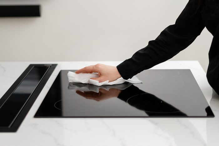 Woman cleaning glass induction stove in kitchen
