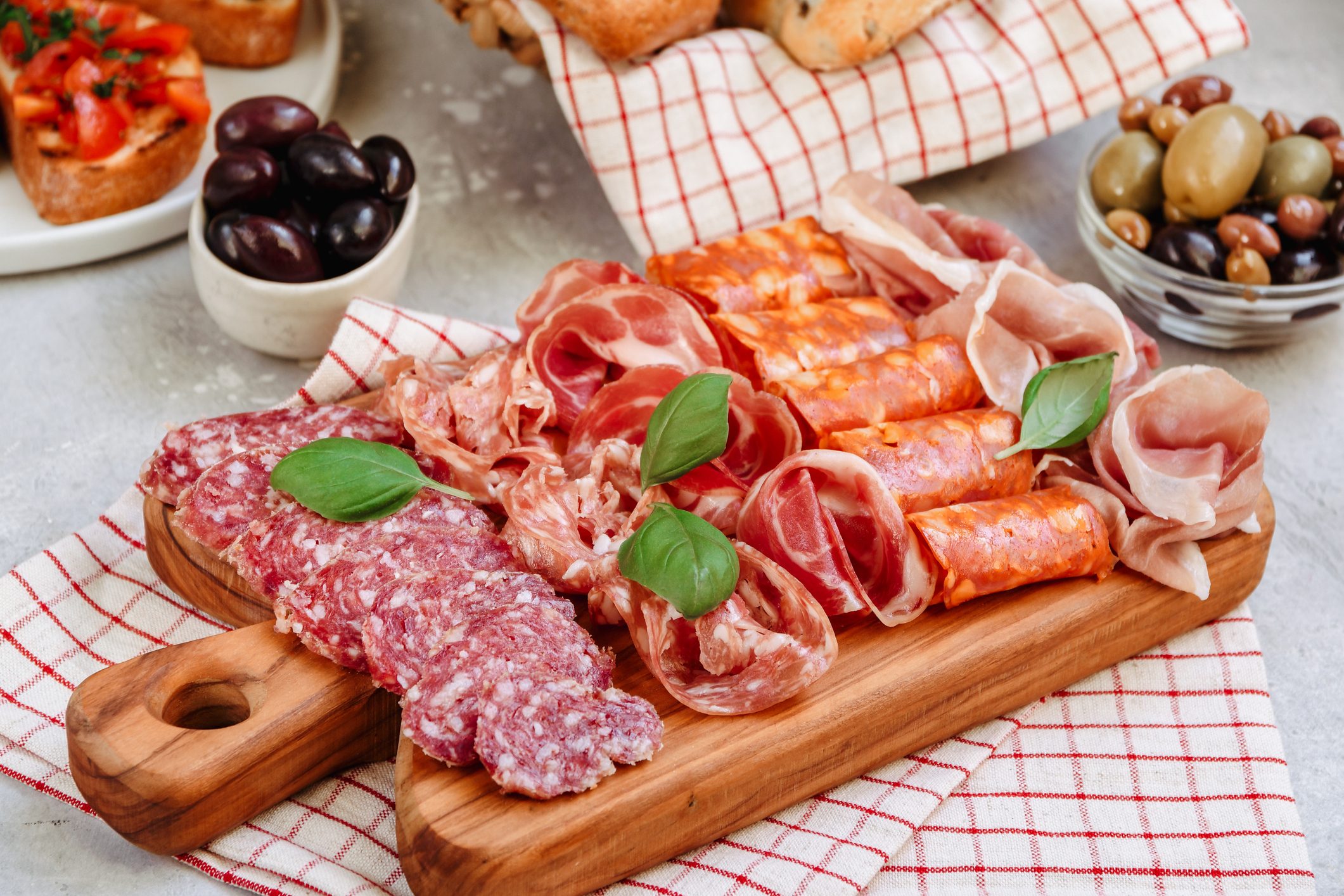 Food antipasto prosciutto ham, salami, olives and bread and Tomato and basil bruschetta Charcuterie board. Two glasses of white wine or prosecco