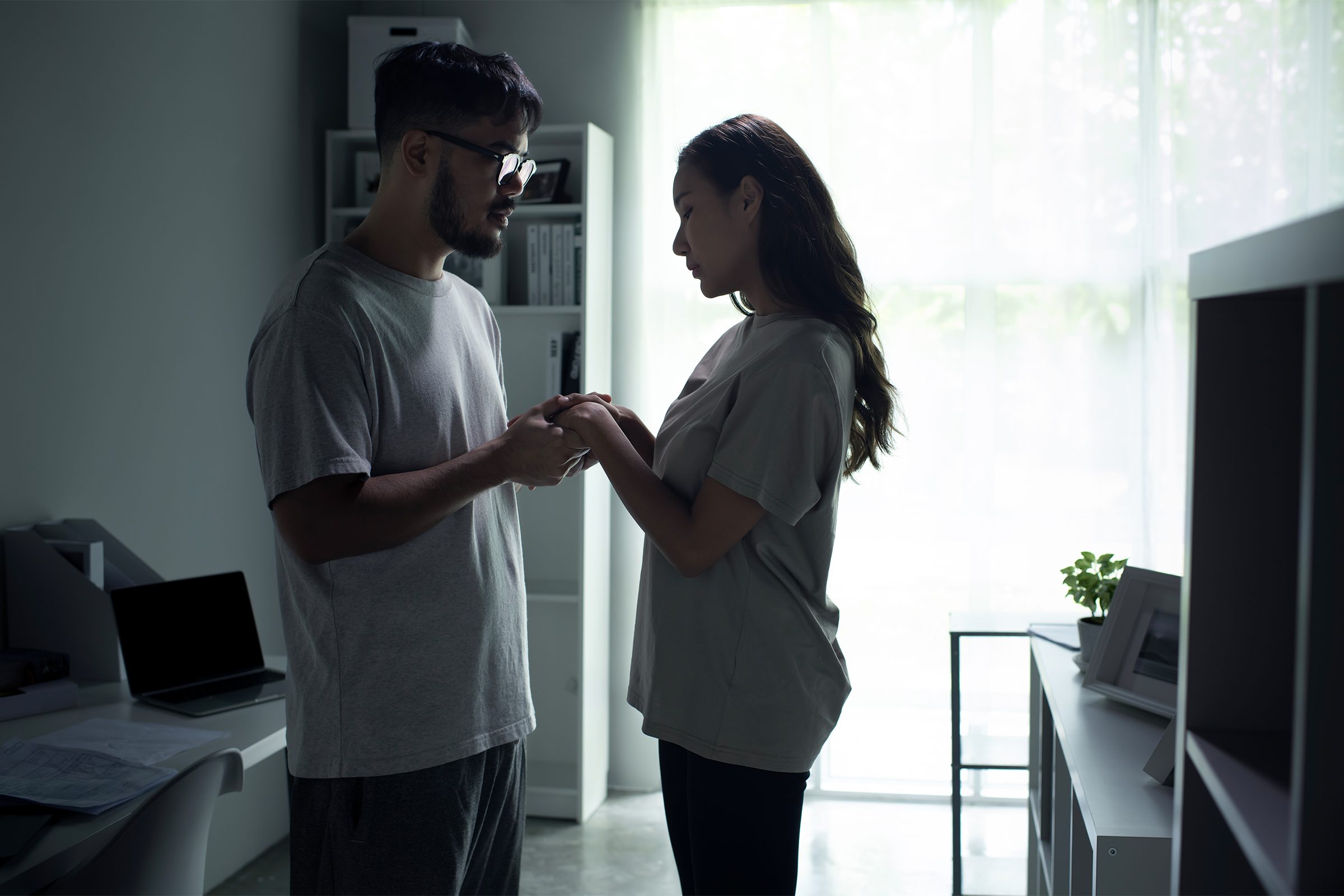 Young Asian couple holding hands and making up after a fight