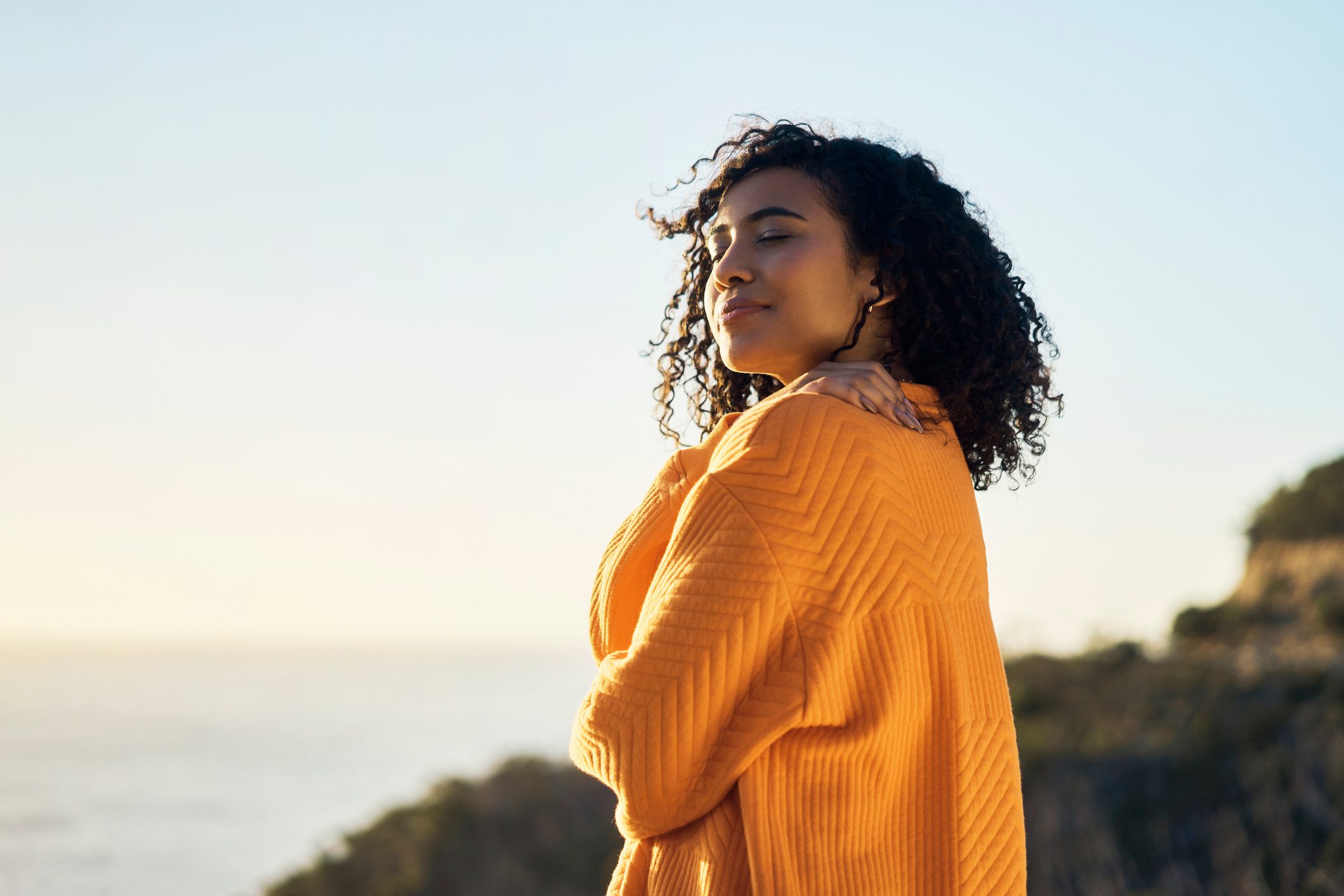 Relax, beach or summer with a woman outdoor and the horizon, sea or ocean in the background during summer. Freedom, self love and nature with a young female on holiday or vacation and hugging herself