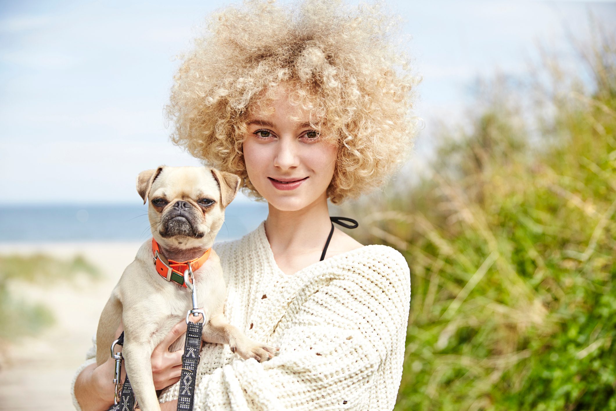 Portrait of smiling young woman holding dog on her arms