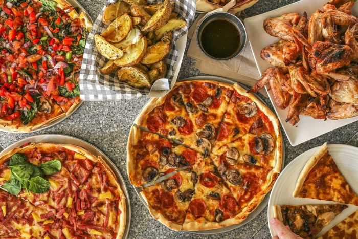 Overhead view of pizza, potato wedges and chicken wings