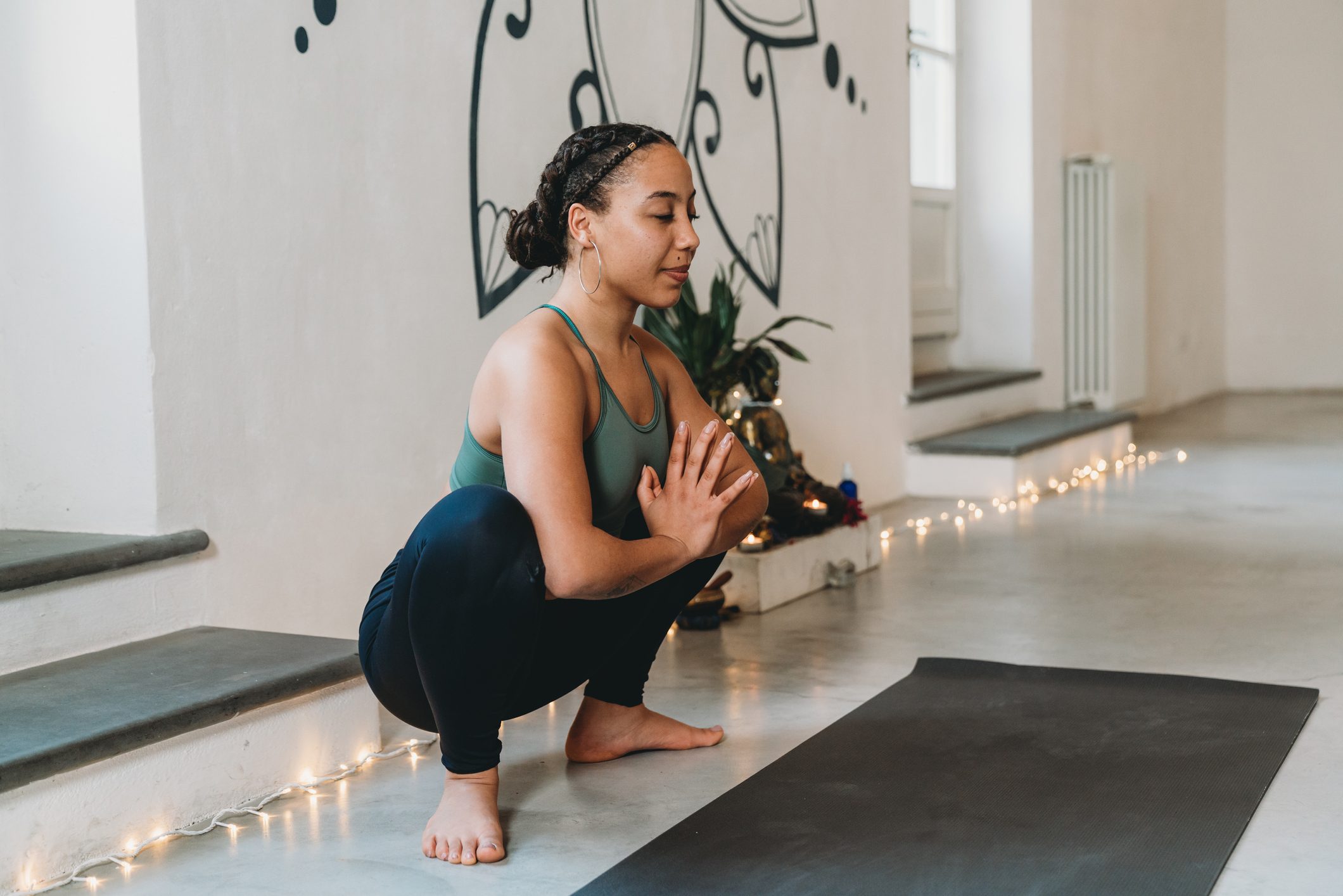 Young adult woman practicing yoga in garland position