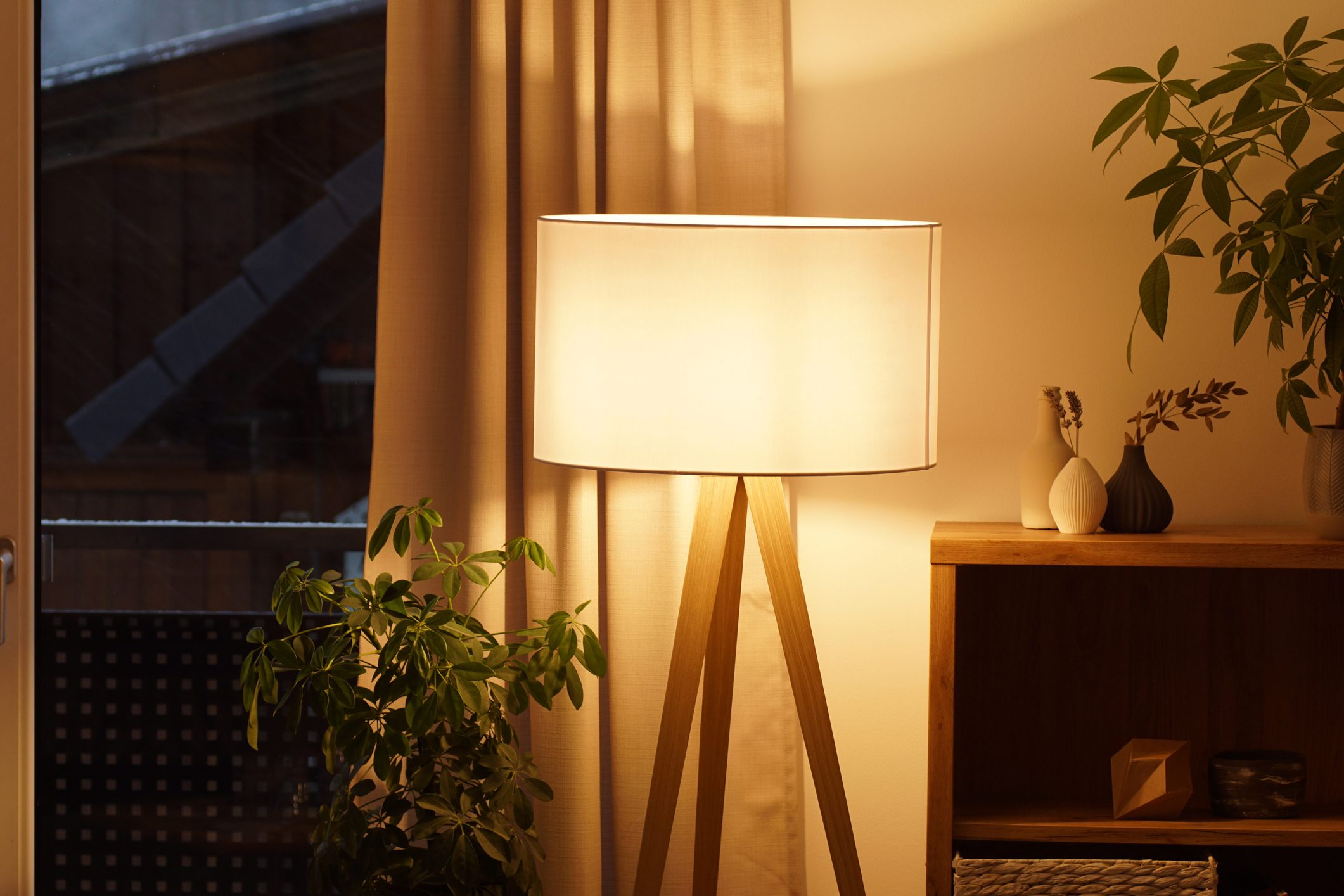 View of tripod lamp in a cozy living room spending warm light