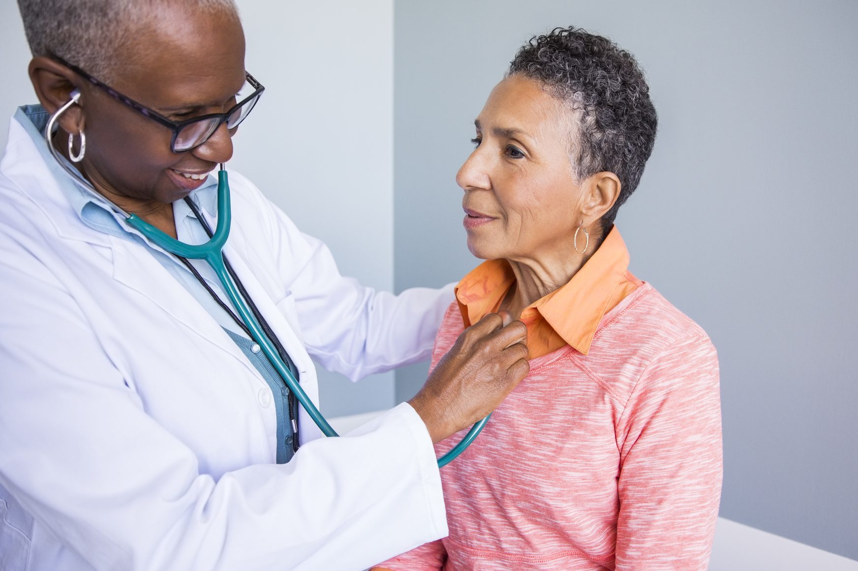 Senior female doctor examining smiling patient in hospital