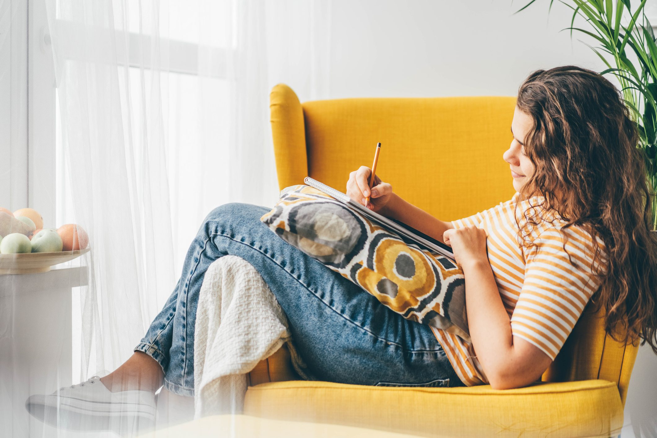 Woman drawing in a sketchbook at home.