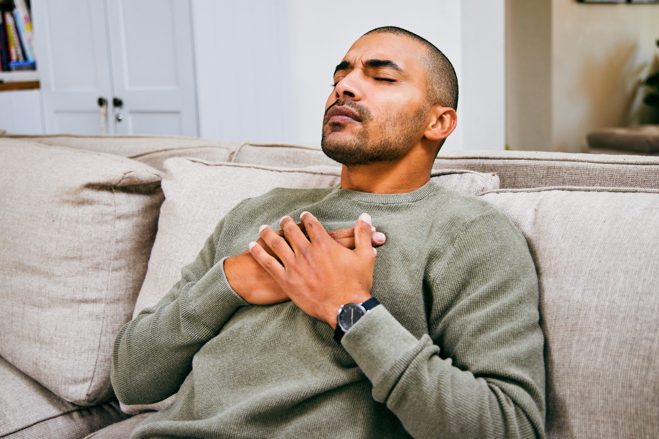 Shot of a young man experiencing chest pains at home