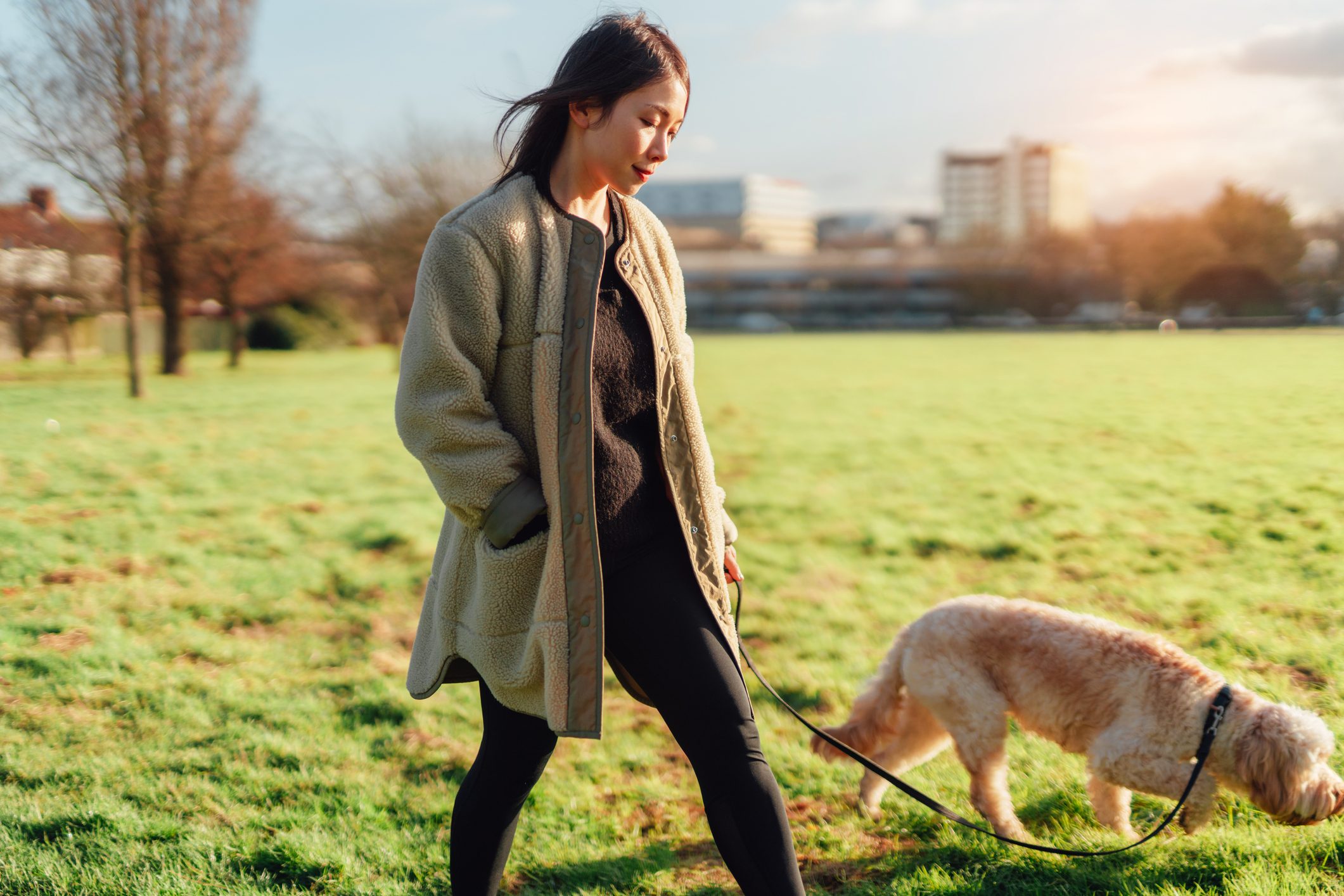 Young Asian woman walking her dog in the park on a sunny day