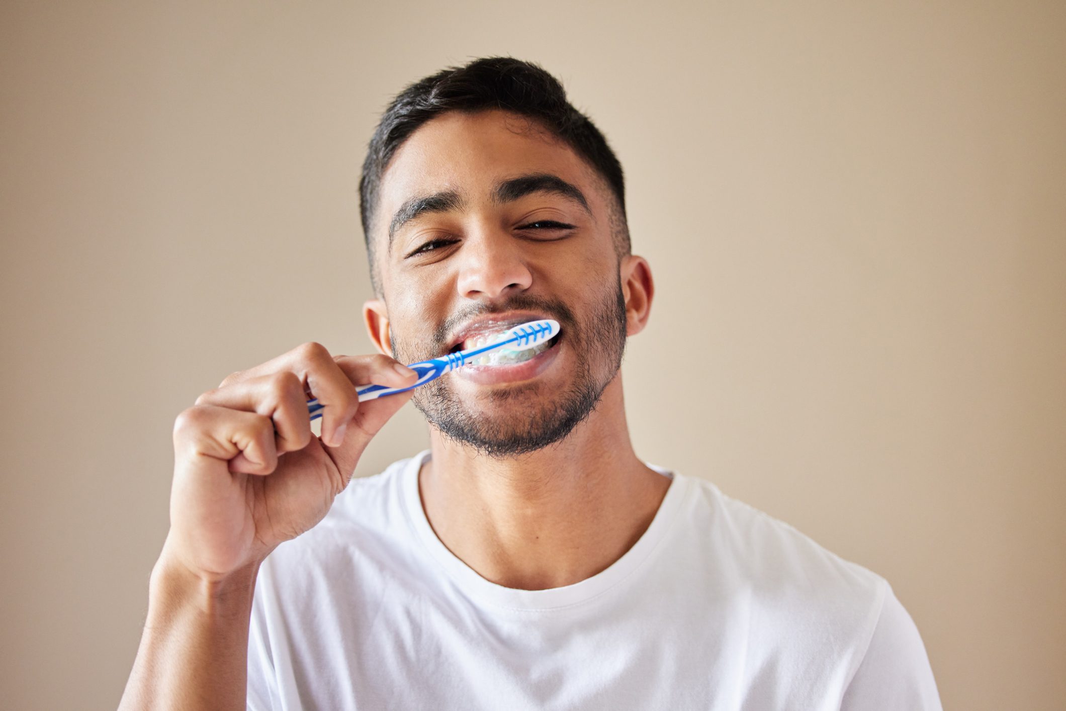 Studio shot of a handsome young man brushing his teeth against a studio background