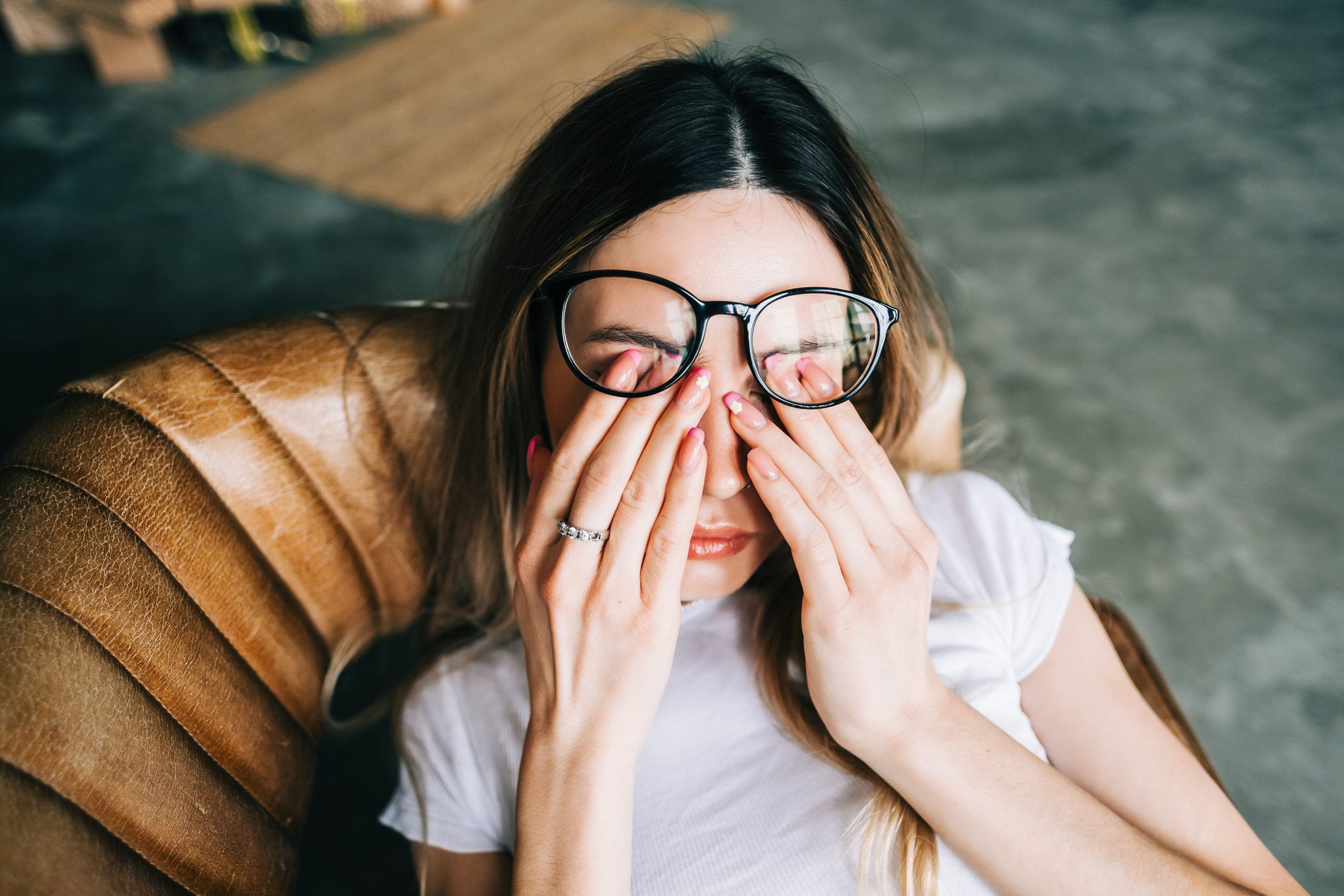 Young woman rubs her eyes after using glasses. Eye pain or fatigue concept.