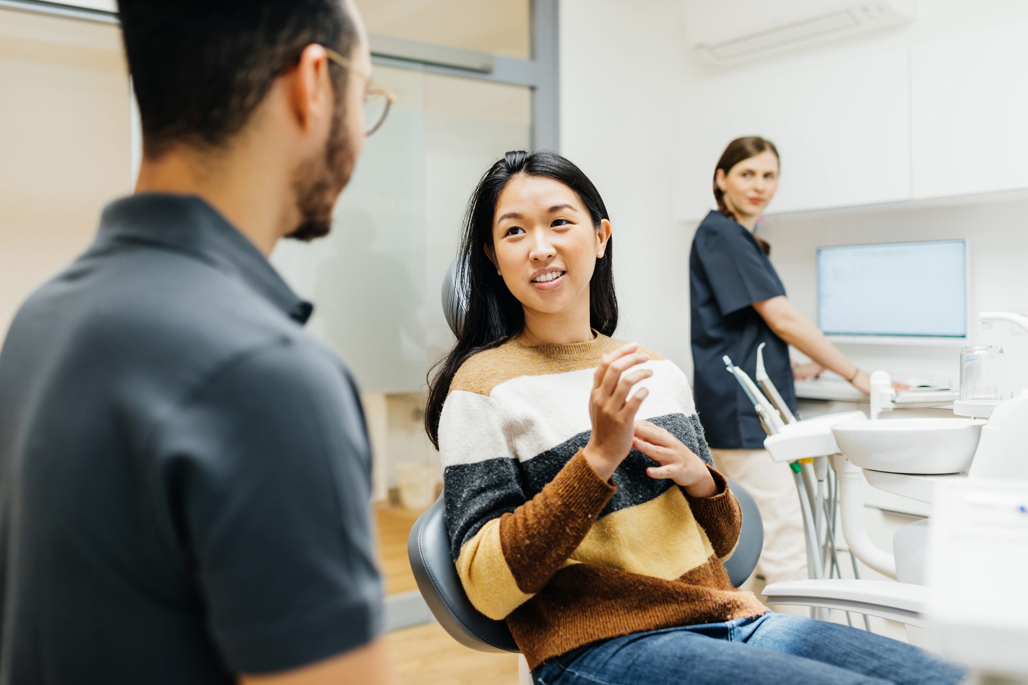 Young Woman Talking To Dentist While Sitting In Surgery