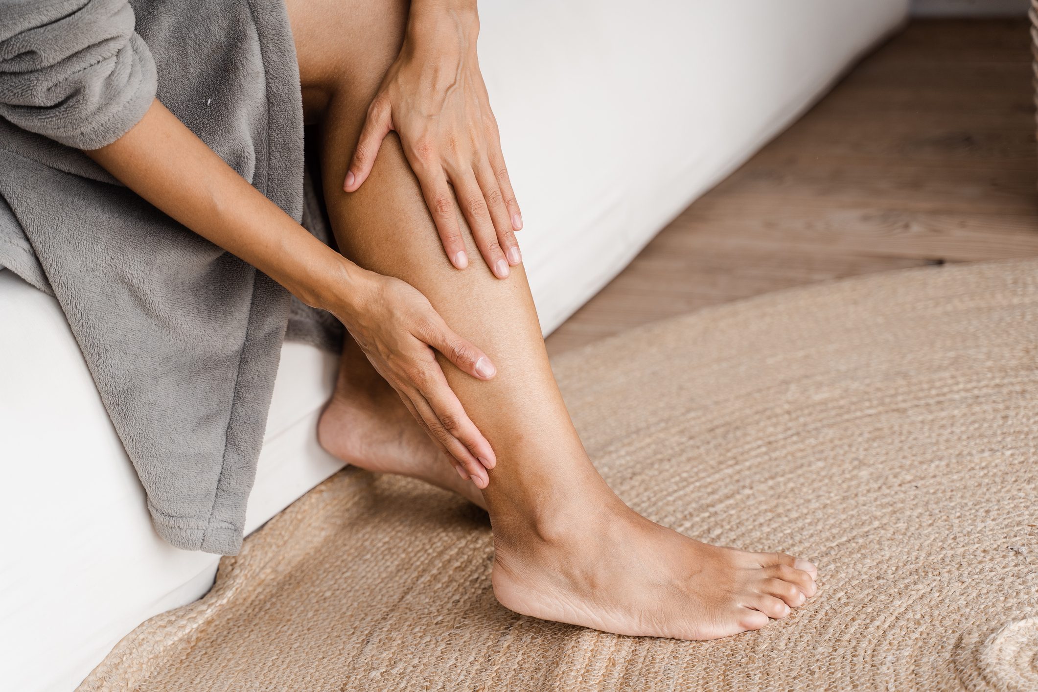 Deep vein thrombosis and varicose of african woman. Girl touching her legs and looking at veins. Sclerotherapy procedure at visiting vascular surgeon doctor.