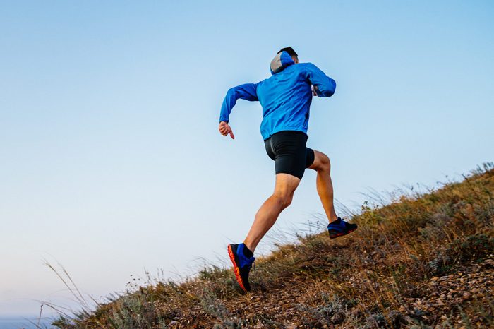 back runner running uphill in background sky