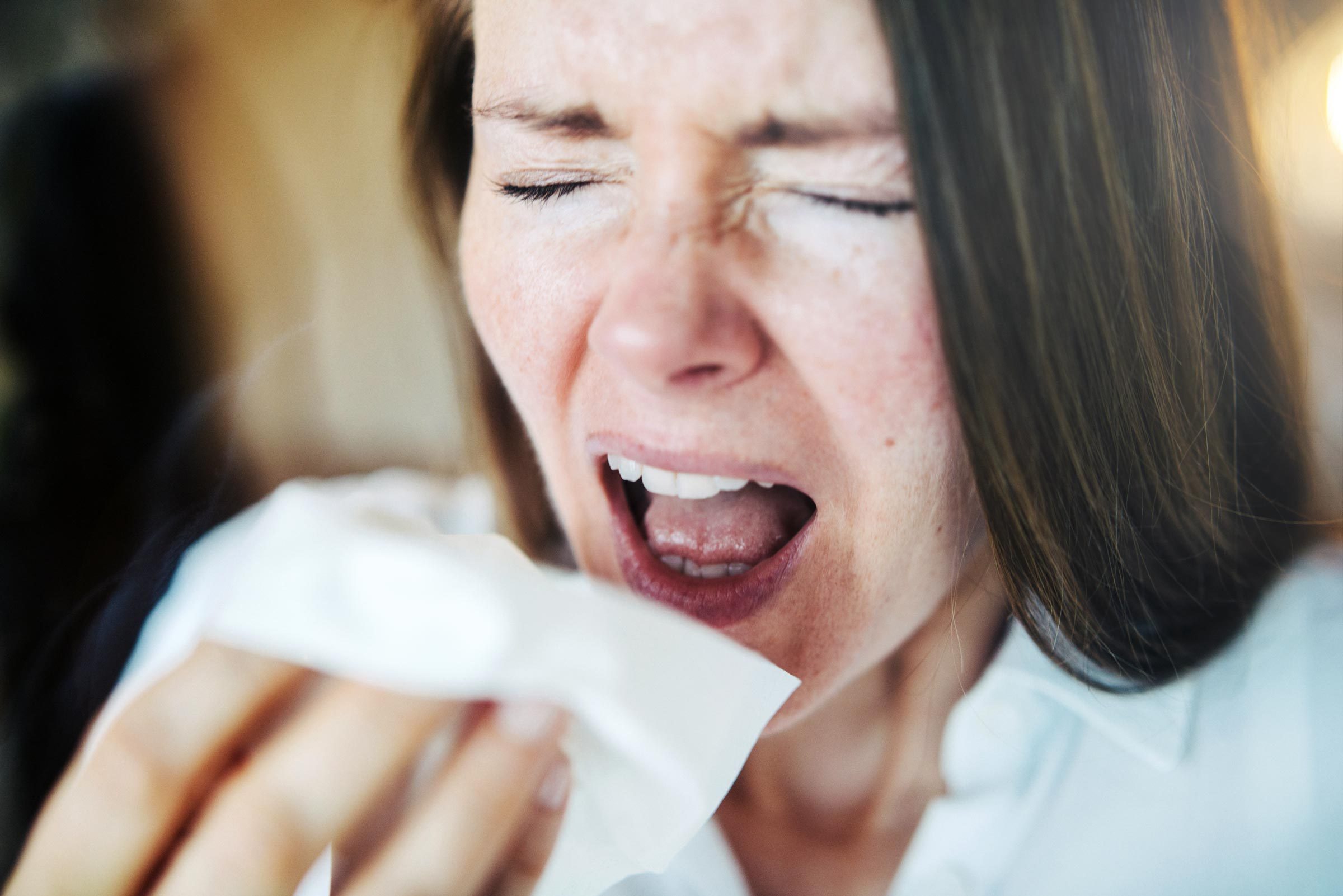 woman sneezing into a tissue