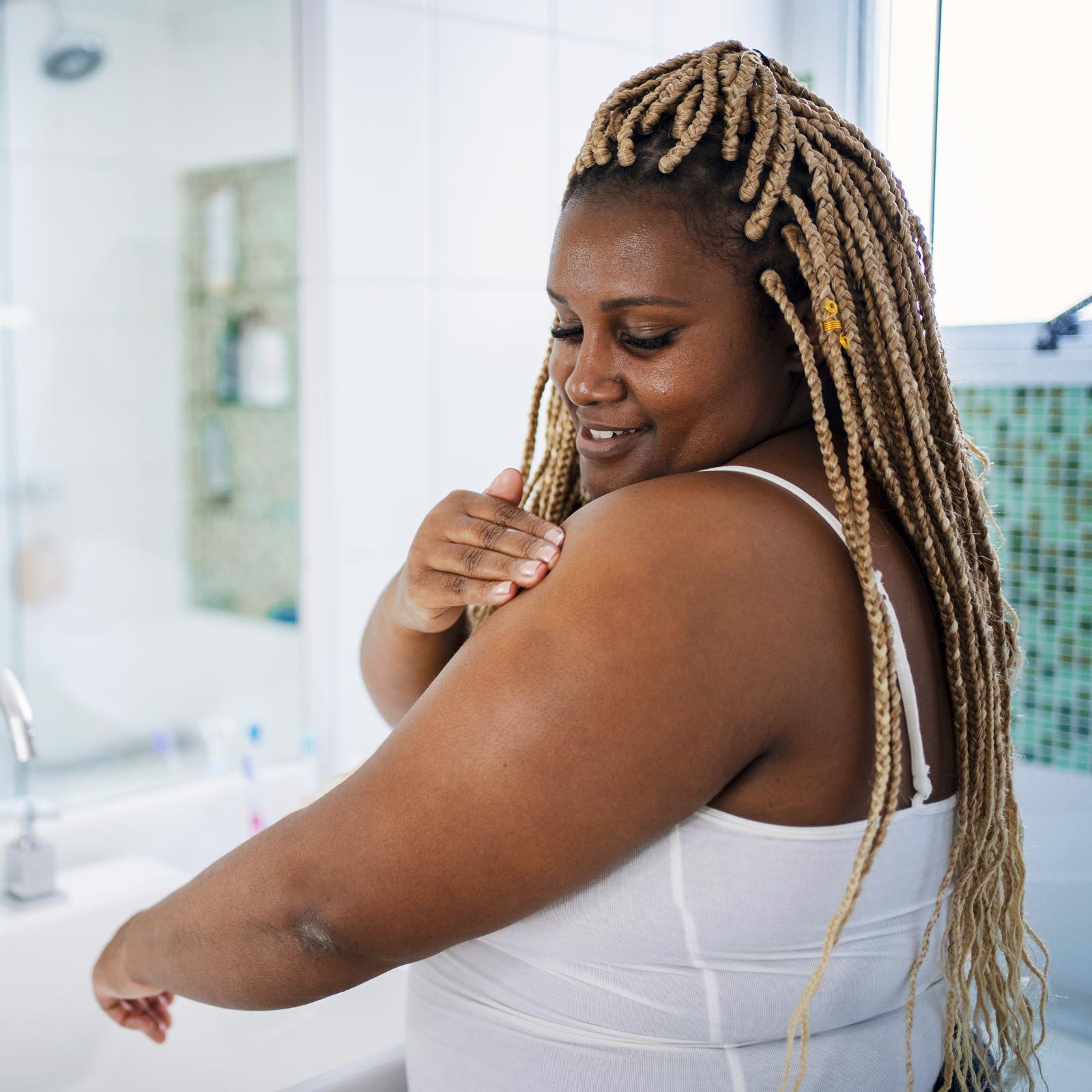 African American woman in her daily skin care routine in the bathroom.