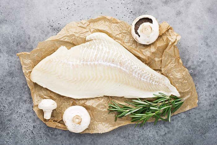 Fillet of sea white cod fish on parchment with fresh raw champignons before cooking. Zero waste kitchen. Healthy food seafood. Top view, space.