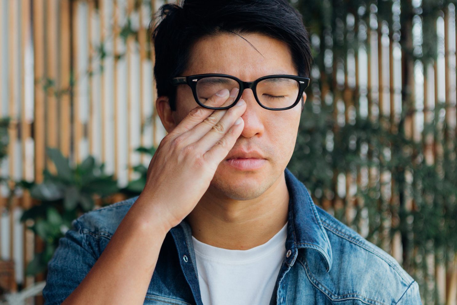 Young Man Rubbing Eye With Hand