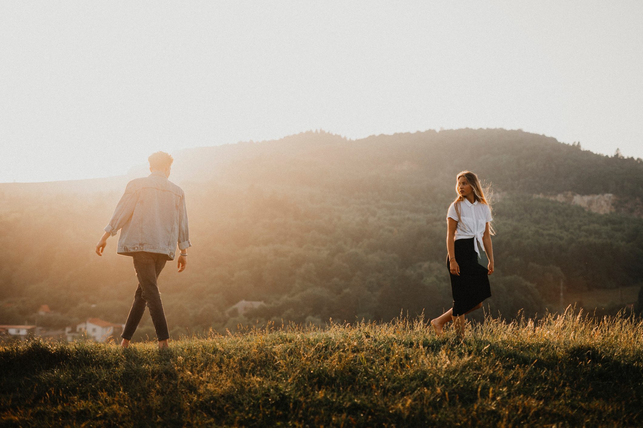 Portrait of young couple on a walk outdoors in nature, walking away from each other.