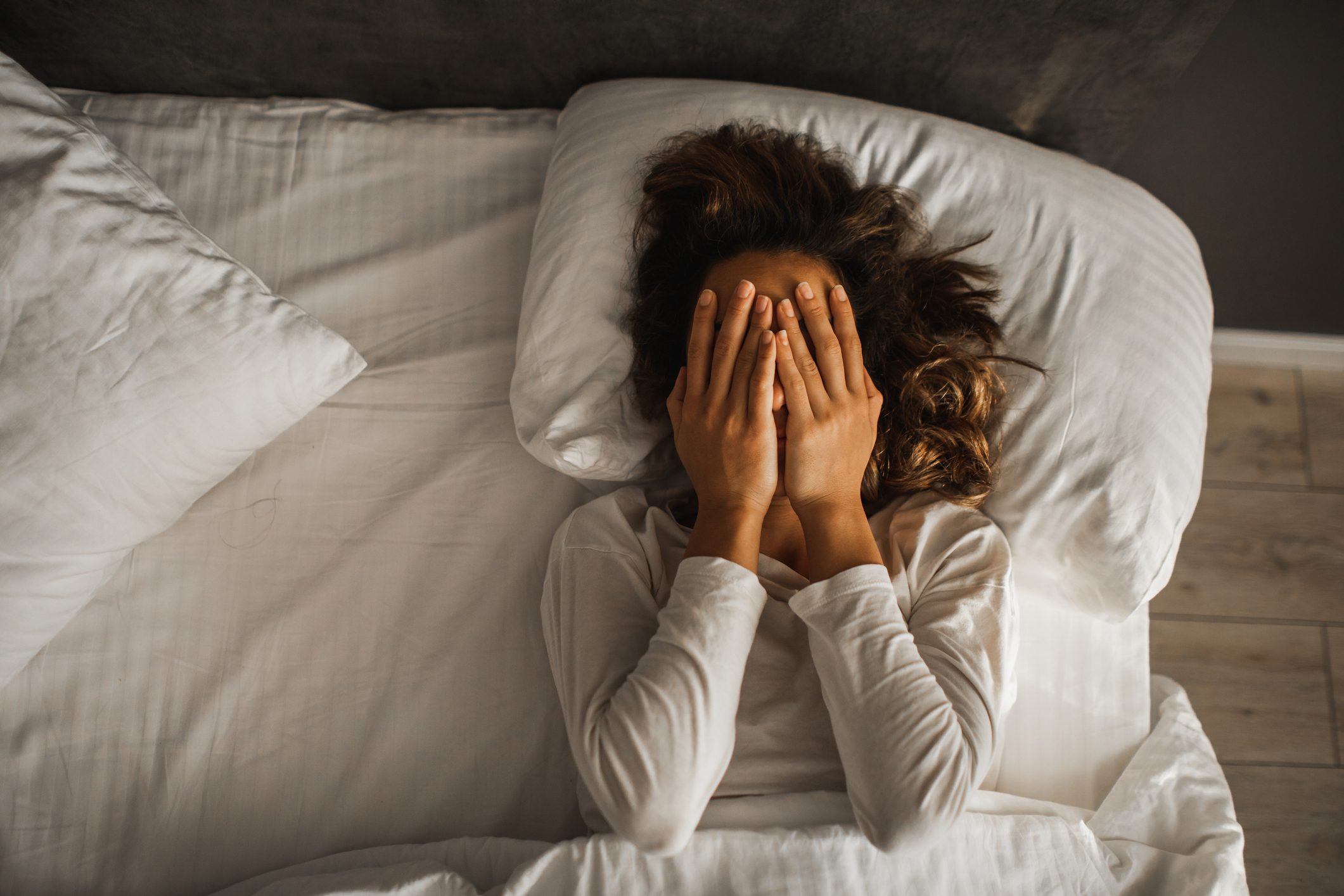 Woman in depression closed face with hands and crying in bed. Melancholy mood, mental health. Life problems