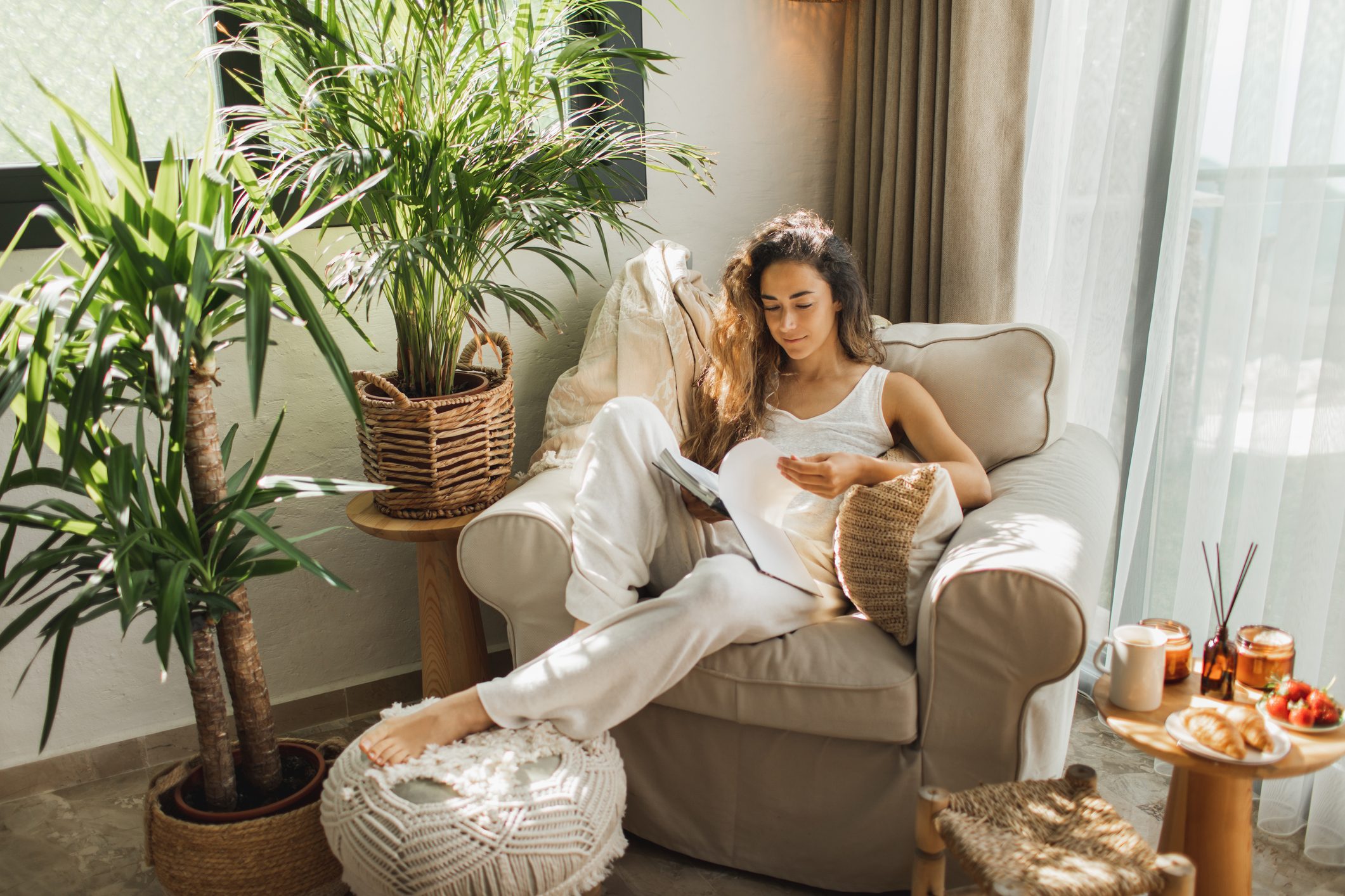 Woman at home reading book and drinking coffee.