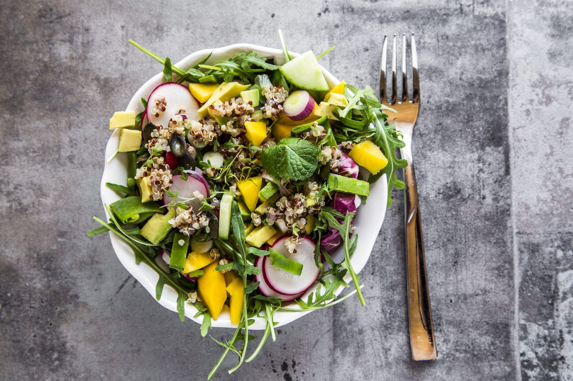 Mango quinoa salad with rocket, avocado, cucumber, red radishes and pumpkin seeds