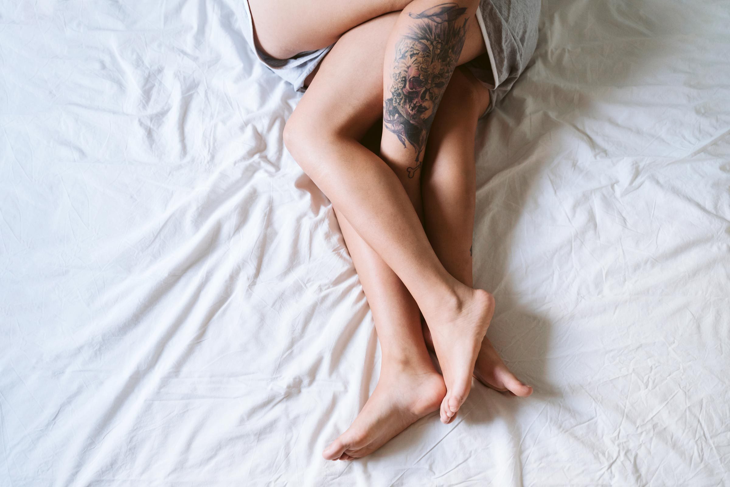 Lesbian couple legs lying on bed at home