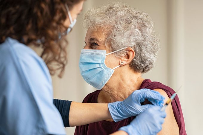 General practitioner vaccinating old patient in private clinic