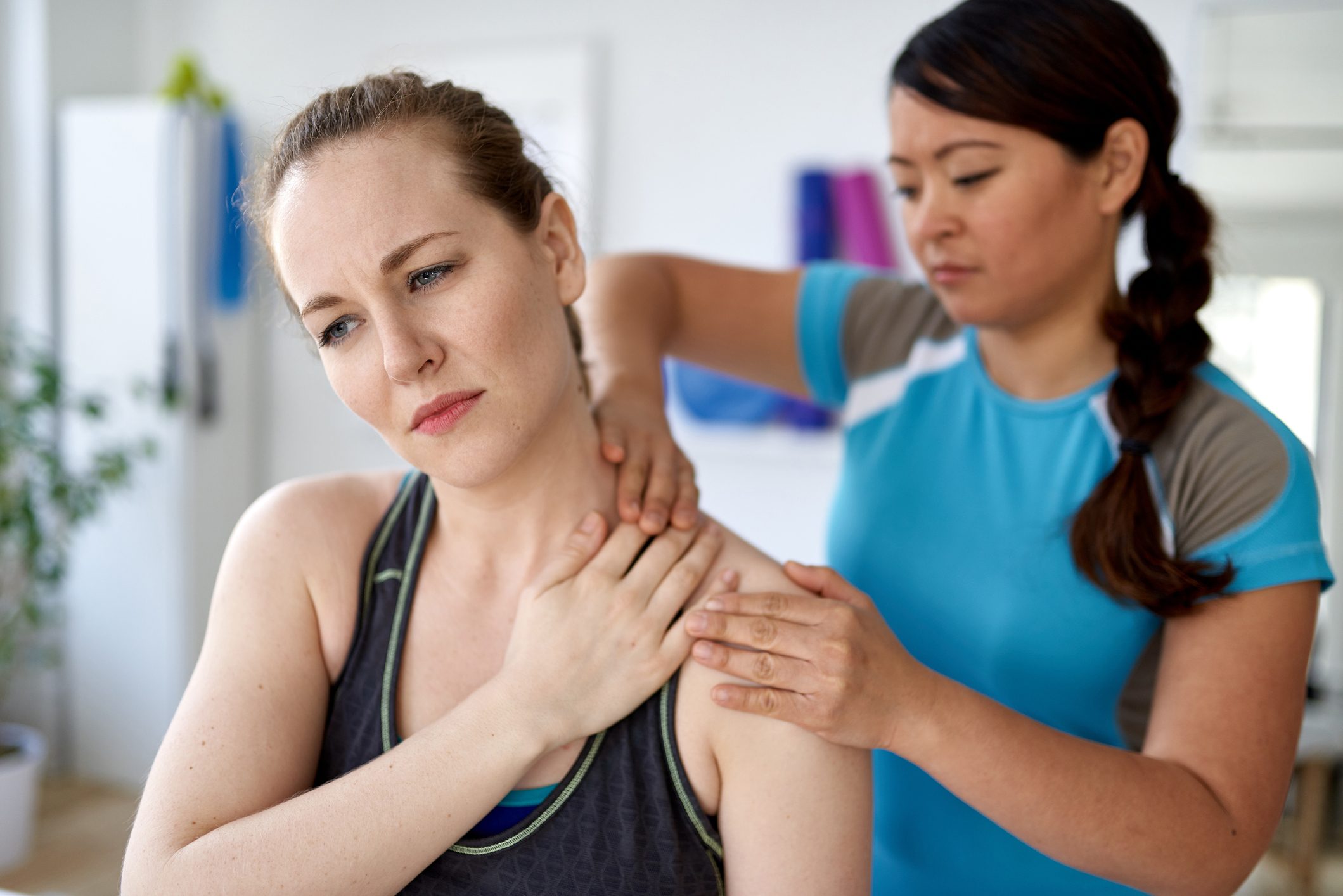 Chinese woman physiotherapy professional giving a treatment to an attractive blond client in a bright medical office