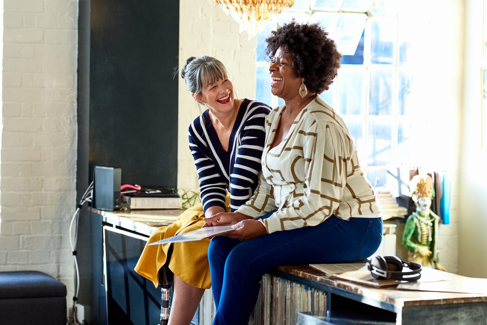 Mature women laughing together in stylish loft apartment