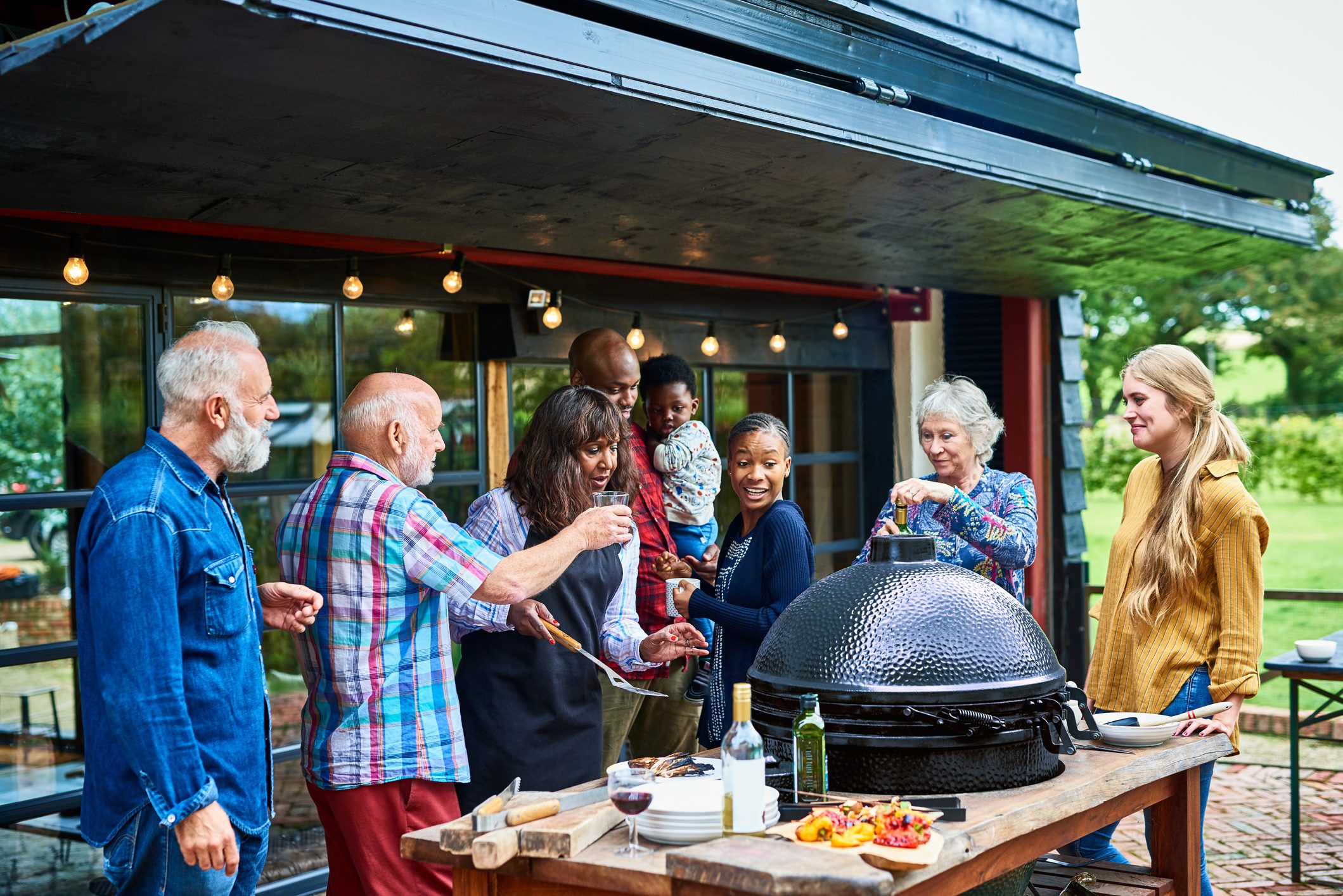 Multi generational family standing around barbecue