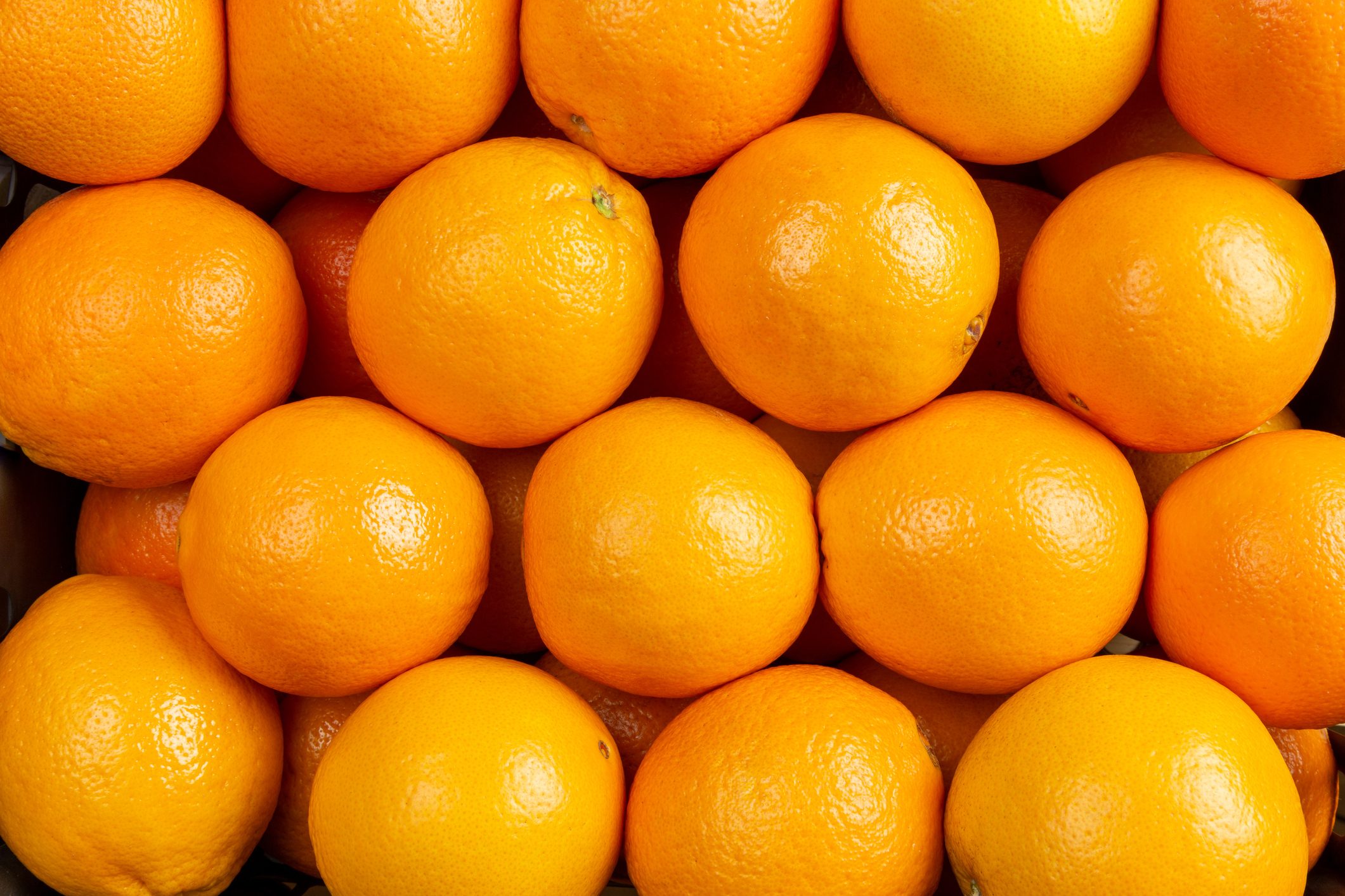 Oranges fruit background. Closeup on a heap of oranges stacked togather and wraped with red paper to preserve freshness.